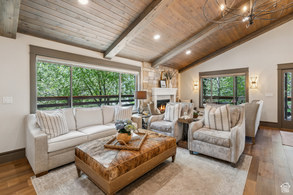 Living area with wooden ceiling, hardwood / wood-style floors, a chandelier, healthy amount of natural light, and a glass covered fireplace