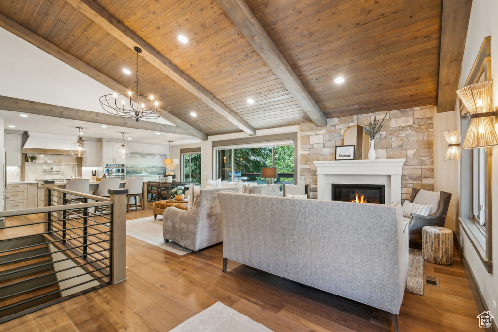 Living room featuring a glass covered fireplace, wood finished floors, a chandelier, and wood ceiling