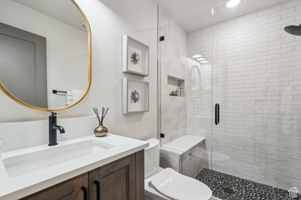 Bathroom with a stall shower, toilet, vanity, and recessed lighting