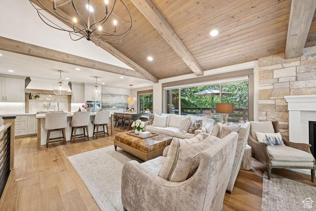 Living area featuring light wood-style floors, a chandelier, recessed lighting, high vaulted ceiling, and a fireplace