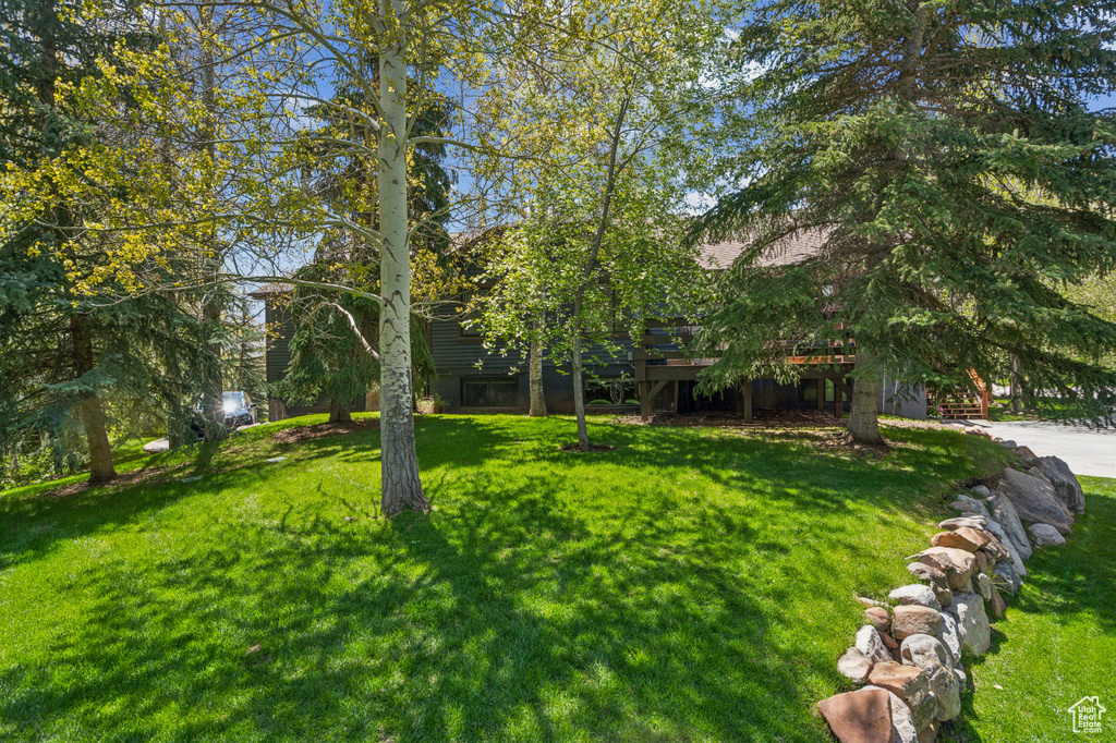 View of green lawn featuring a wooden deck