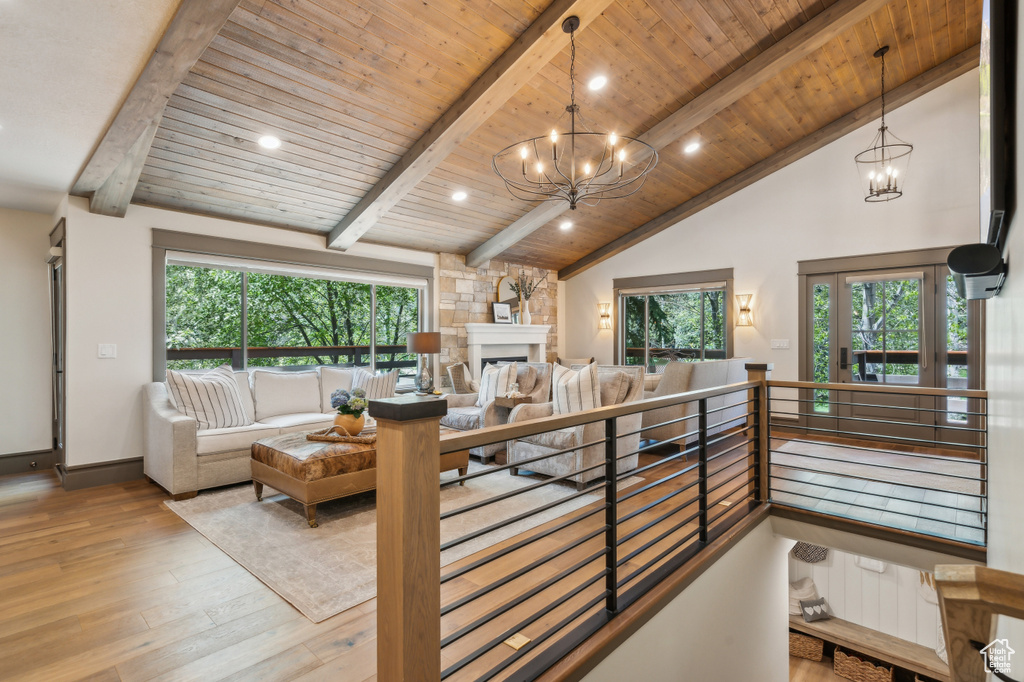 Living room with a chandelier, hardwood / wood-style flooring, wooden ceiling with exposed beams, recessed lighting, and a large fireplace