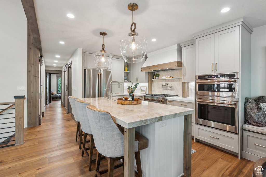 Kitchen featuring custom exhaust hood, stainless steel appliances, open shelves, recessed lighting, and backsplash