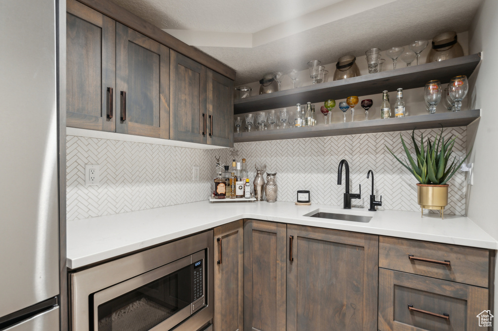 Indoor wet bar with appliances with stainless steel finishes and tasteful backsplash