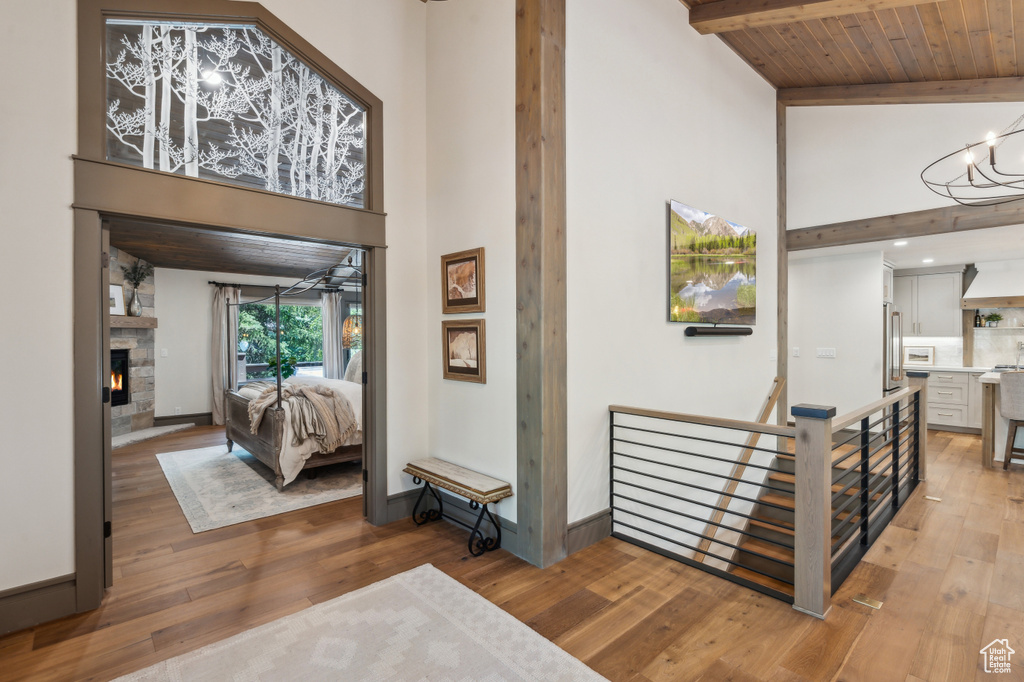 Hallway featuring a high ceiling, light wood-style flooring, a chandelier, an upstairs landing, and baseboards