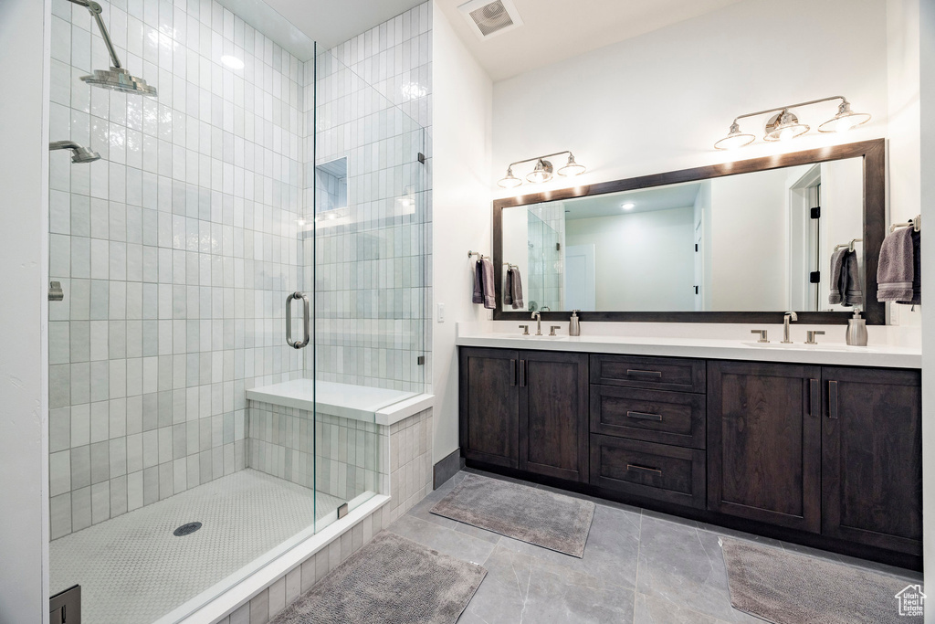 Full bathroom featuring a shower stall, double vanity, and tile patterned flooring