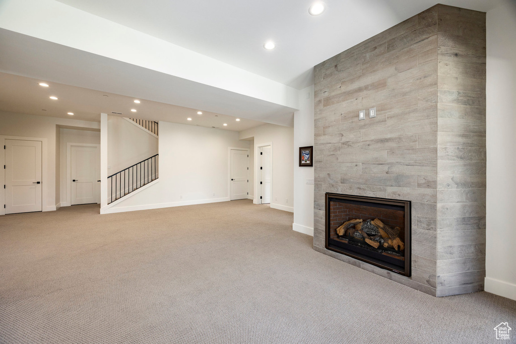 Unfurnished living room featuring recessed lighting, carpet floors, a fireplace, baseboards, and stairs