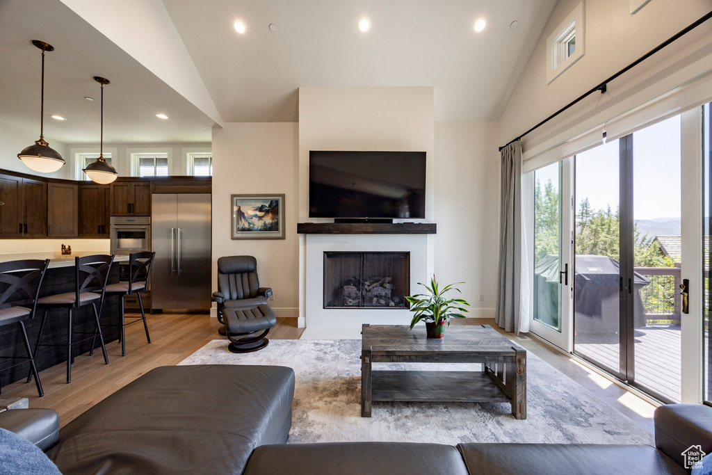 Living area featuring a fireplace, recessed lighting, light wood-type flooring, high vaulted ceiling, and baseboards