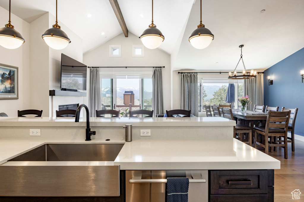 Kitchen with light wood-style floors, a sink, beam ceiling, open floor plan, and a chandelier