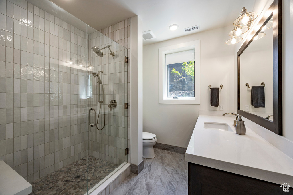 Full bathroom with double vanity, a shower stall, toilet, and baseboards
