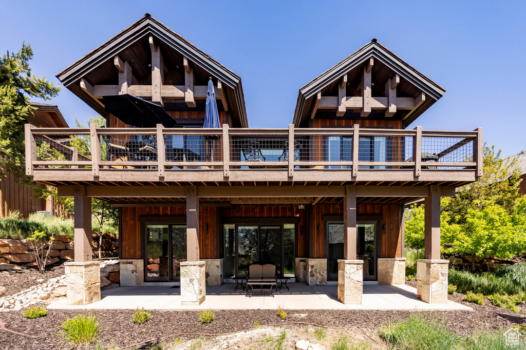 Rear view of house featuring board and batten siding, a wooden deck, and a patio area