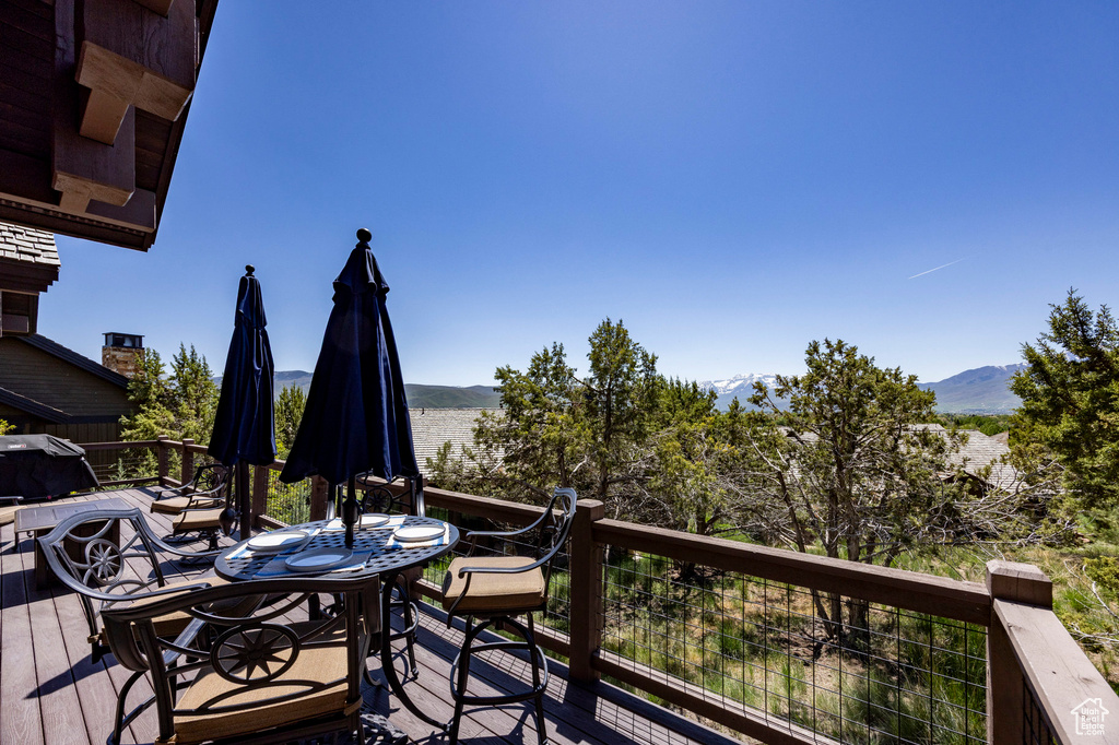 Wooden terrace featuring a mountain view and outdoor dining area