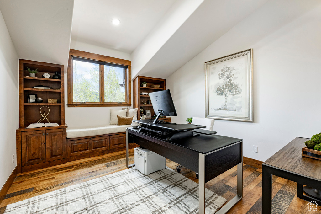 Home office featuring light wood finished floors, baseboards, and vaulted ceiling