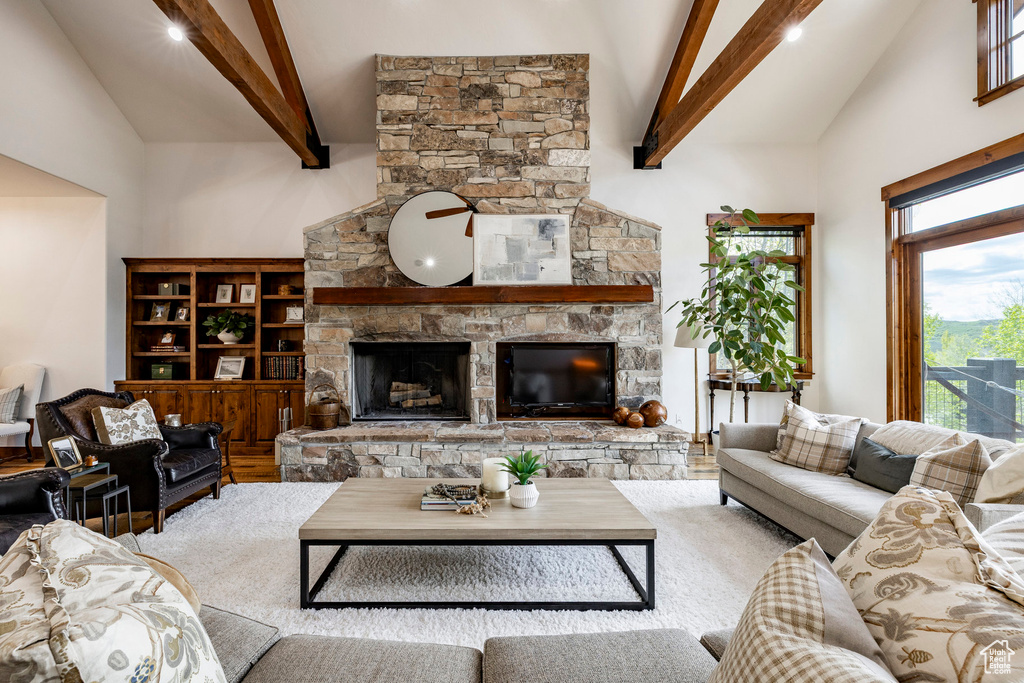 Living room with high vaulted ceiling, beamed ceiling, a stone fireplace, and recessed lighting