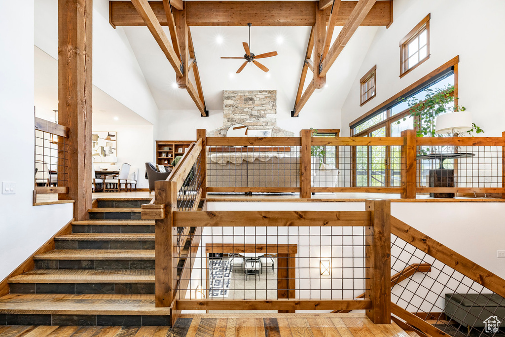 Staircase featuring high vaulted ceiling, a ceiling fan, wood finished floors, and beamed ceiling