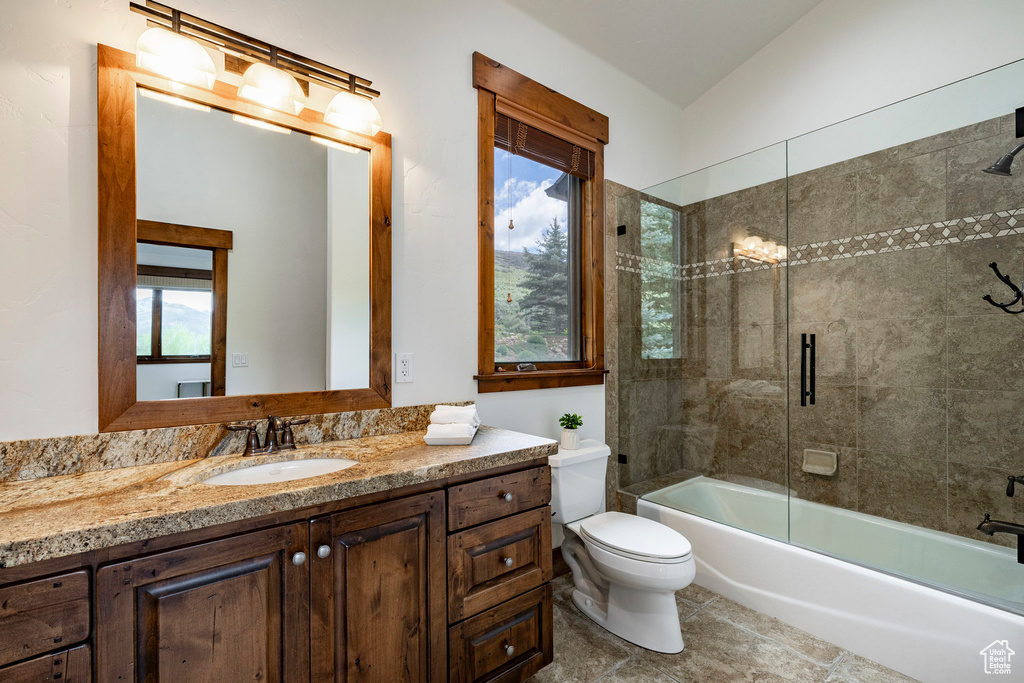 Full bath with toilet, vanity, healthy amount of natural light, enclosed tub / shower combo, and lofted ceiling