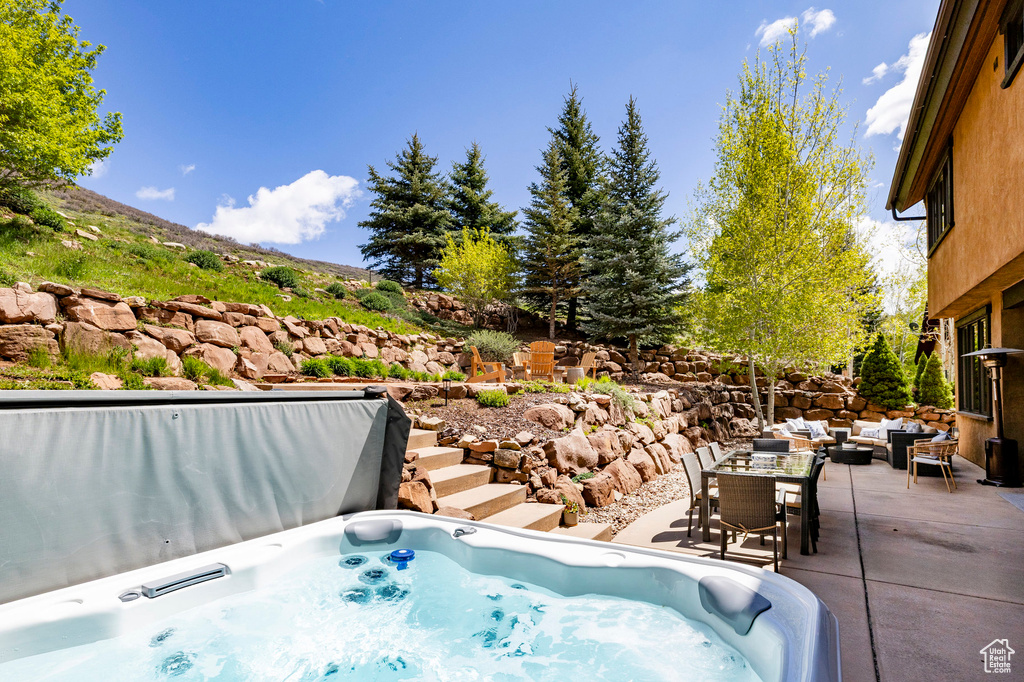 View of swimming pool with a hot tub and a patio