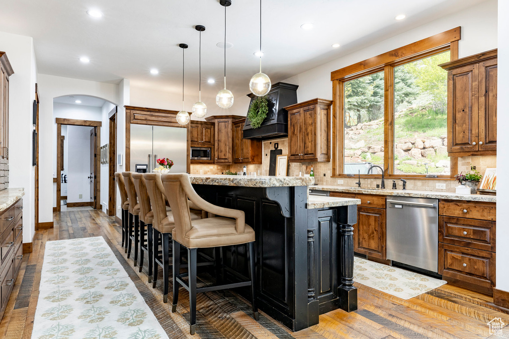 Kitchen featuring appliances with stainless steel finishes, backsplash, a center island, light wood-style flooring, and recessed lighting