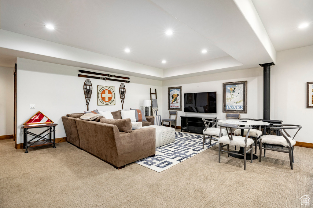 Living area with light colored carpet, baseboards, recessed lighting, a wood stove, and a tray ceiling