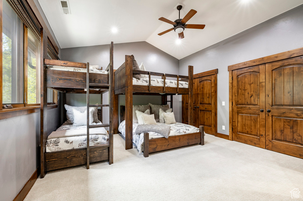 Carpeted bedroom featuring vaulted ceiling, baseboards, and a ceiling fan