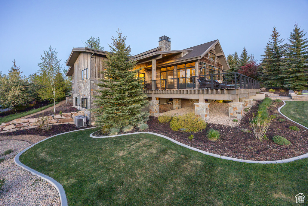 Back of house featuring a chimney, a yard, central AC, and a deck