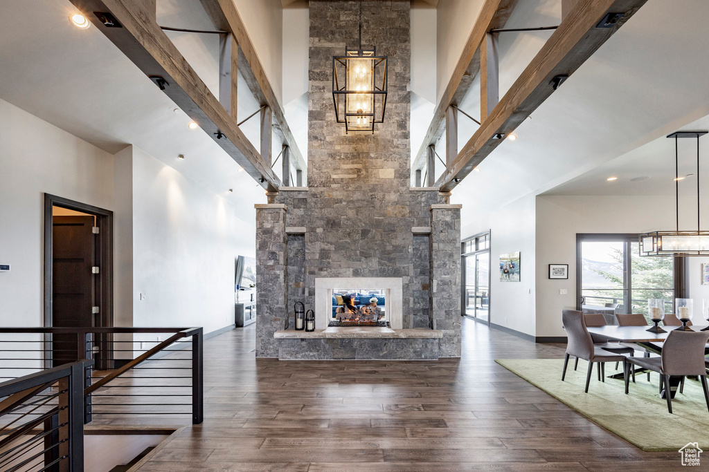 Living room with a high ceiling, a chandelier, wood finished floors, a stone fireplace, and baseboards