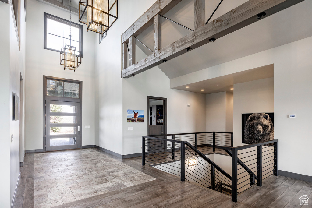 Foyer with a high ceiling, a chandelier, baseboards, and wood finished floors