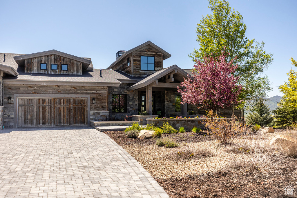 View of front of home with decorative driveway and stone siding