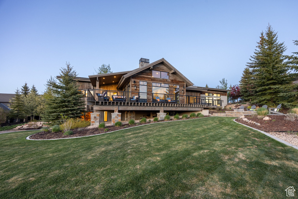 Rear view of property with a chimney, a yard, and a deck