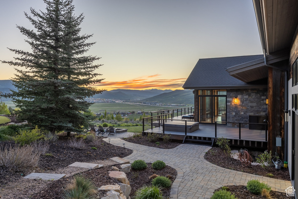 Yard at dusk featuring a patio and a deck with mountain view
