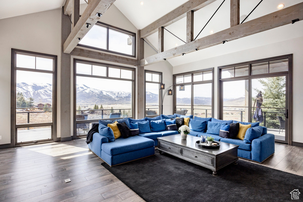 Living room with a mountain view, high vaulted ceiling, hardwood / wood-style floors, baseboards, and beamed ceiling