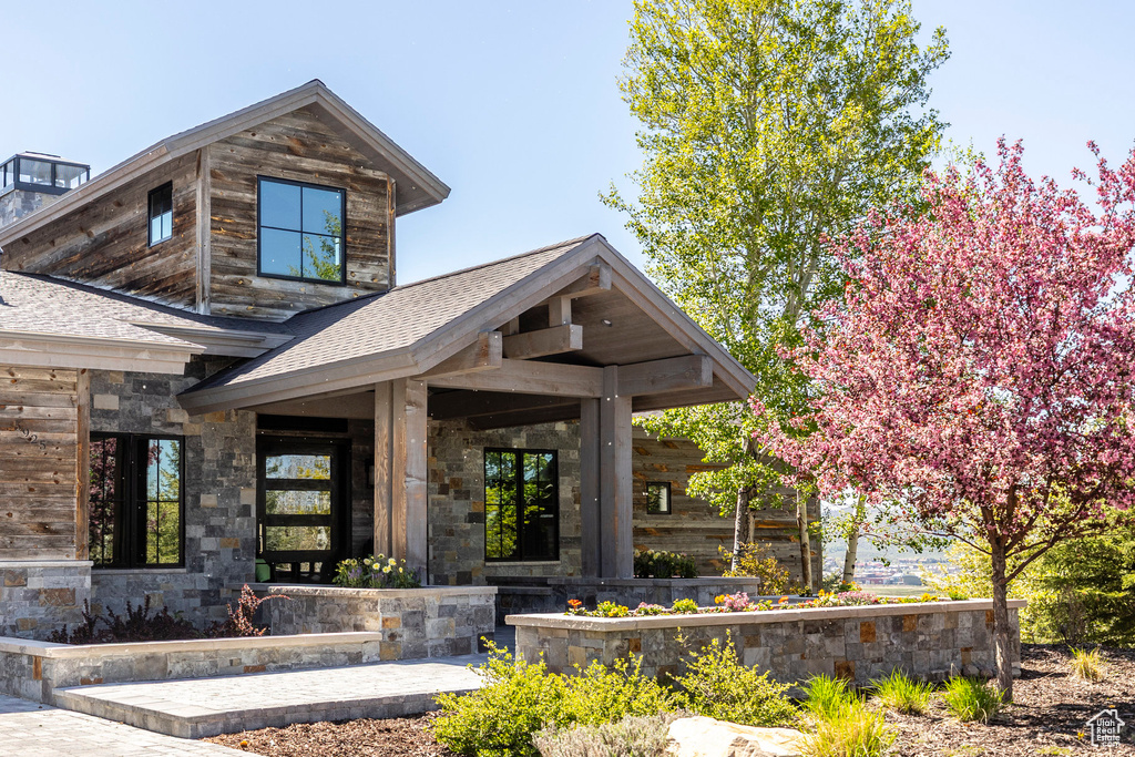 View of front of property featuring roof with shingles and stone siding