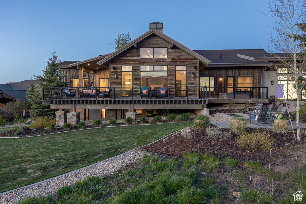 Back of property featuring a yard, a chimney, a wooden deck, and a patio