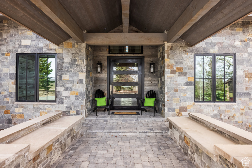 Doorway to property featuring stone siding and a patio