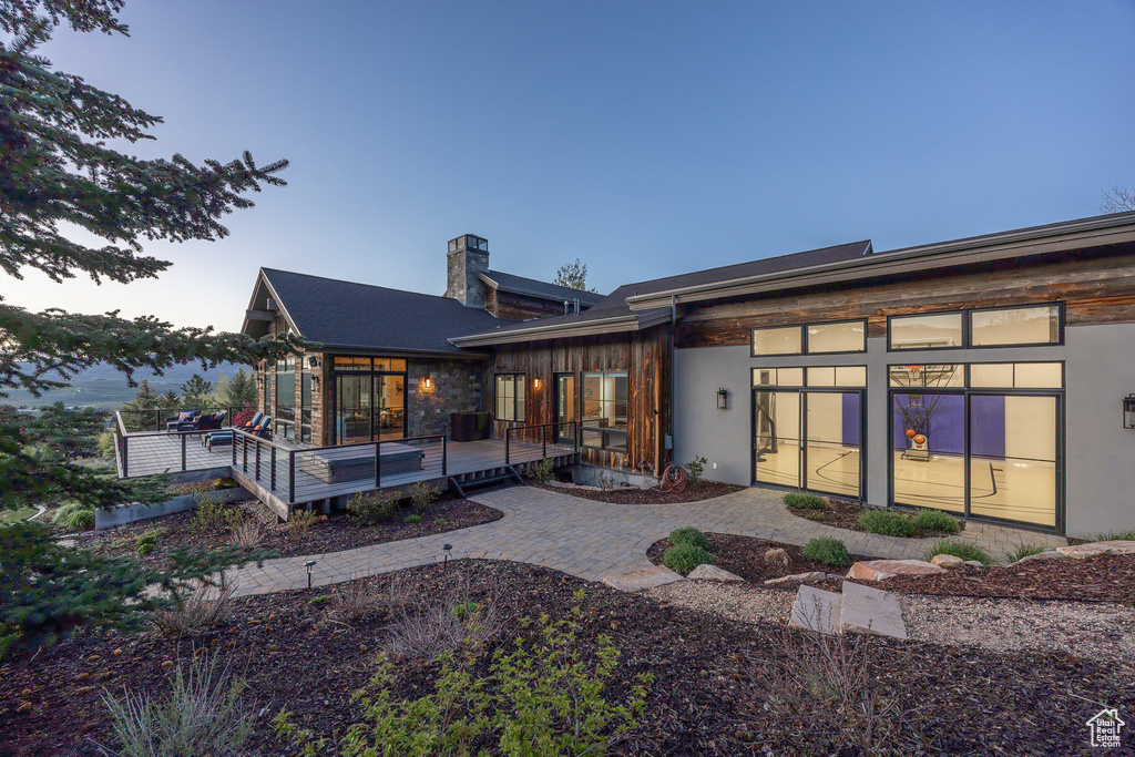 Back of house at dusk featuring a chimney and a wooden deck