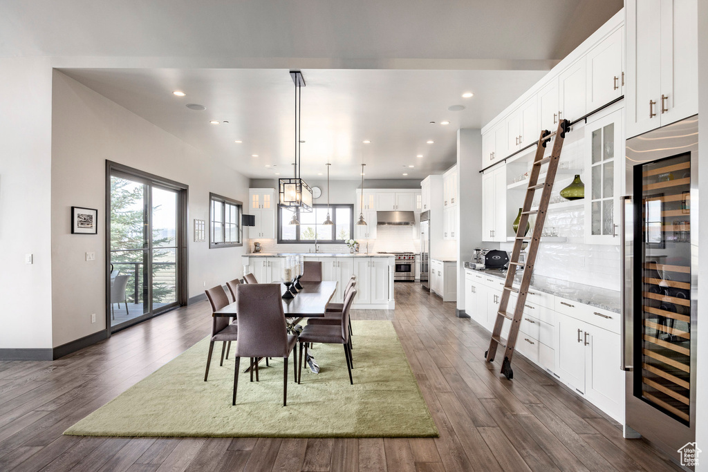 Dining room with beverage cooler, dark wood-type flooring, recessed lighting, and baseboards
