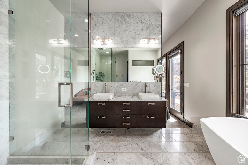 Full bath featuring marble tiled flooring, double vanity, a freestanding tub, and a shower stall