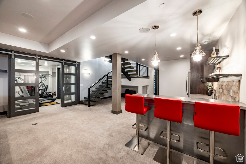Indoor dry bar featuring stairs, recessed lighting, light colored carpet, freestanding refrigerator, and decorative light fixtures