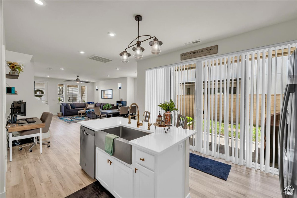 Kitchen with dishwasher, a sink, light wood-style flooring, a center island with sink, and recessed lighting