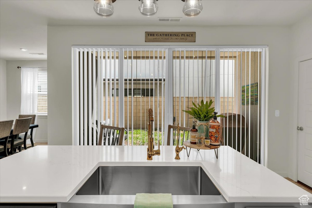 Kitchen with a sink, a kitchen island with sink, and light stone counters