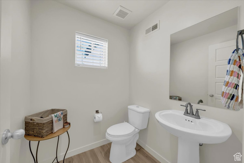 Bathroom featuring wood finished floors, toilet, and baseboards