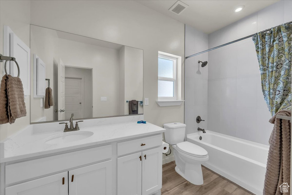 Full bathroom featuring vanity, toilet, shower / bath combo with shower curtain, and wood finished floors