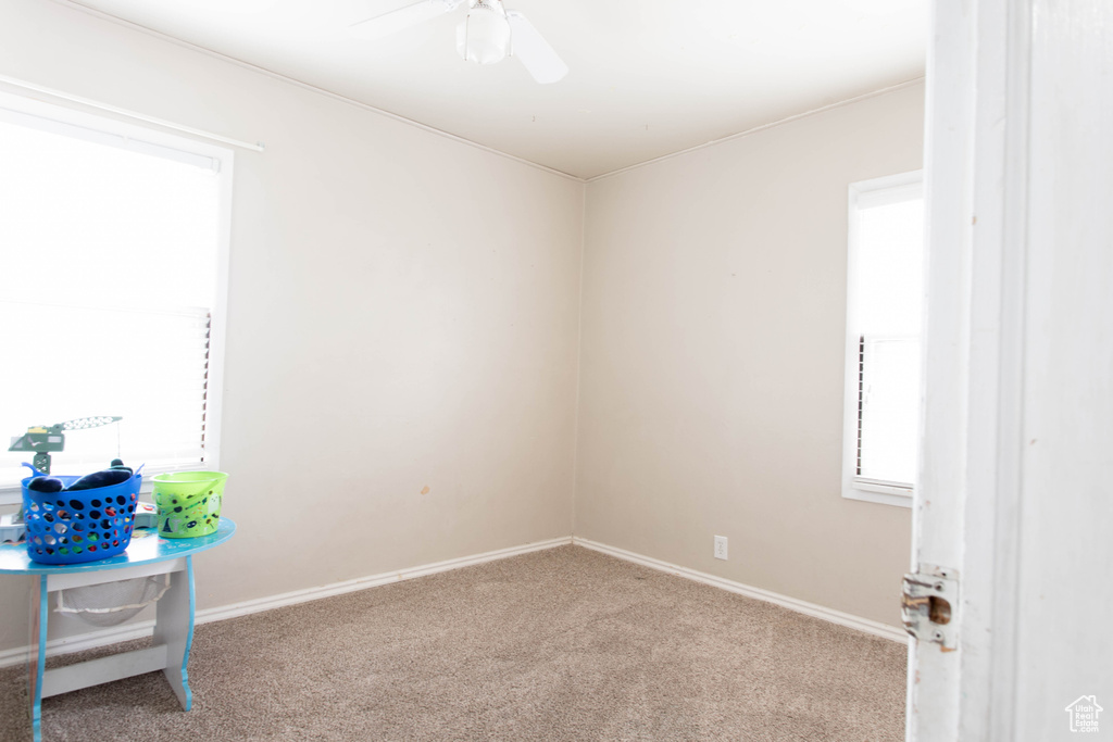 Carpeted empty room featuring a ceiling fan and baseboards