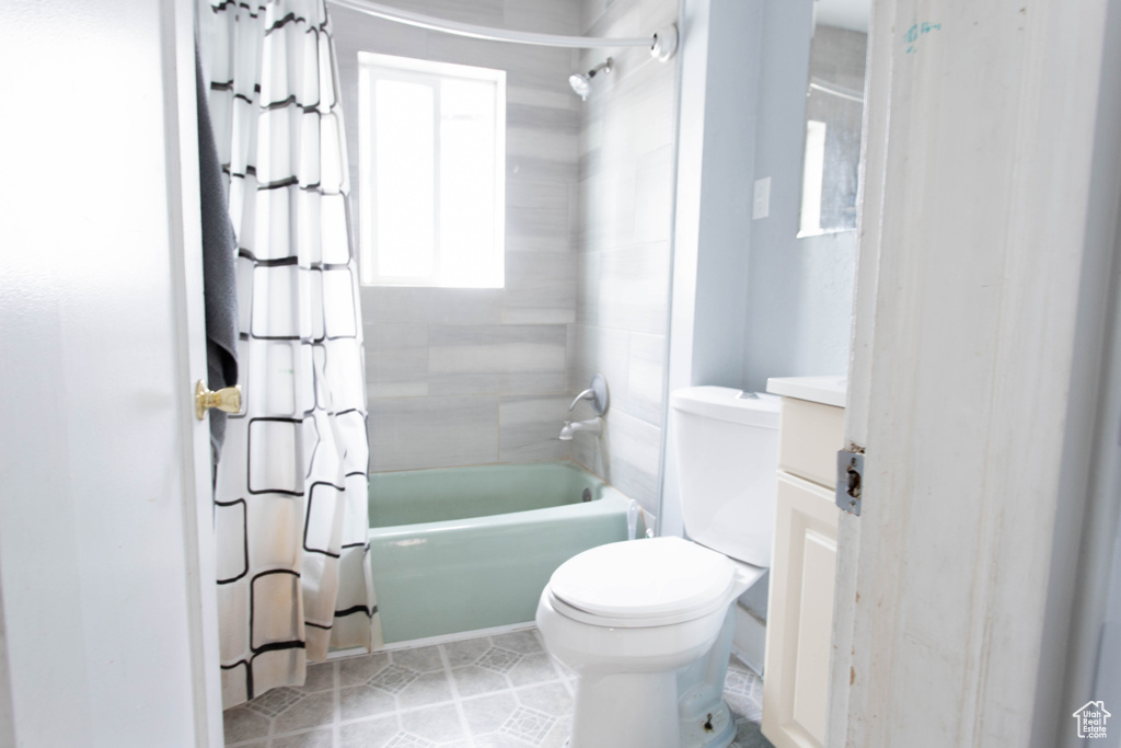 Bathroom with shower / bath combo with shower curtain, toilet, tile patterned floors, and vanity