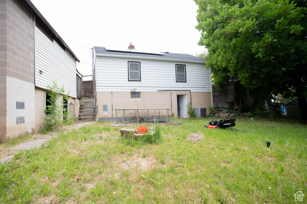 Back of house with central AC, roof mounted solar panels, and stairway