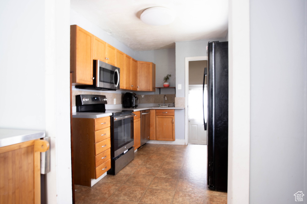 Kitchen featuring stainless steel appliances, a sink, light countertops, and tasteful backsplash