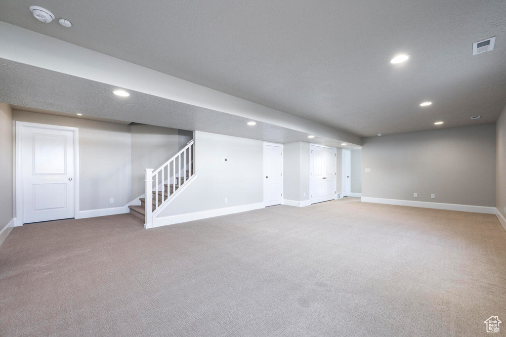 Finished basement featuring carpet floors, baseboards, recessed lighting, and stairway