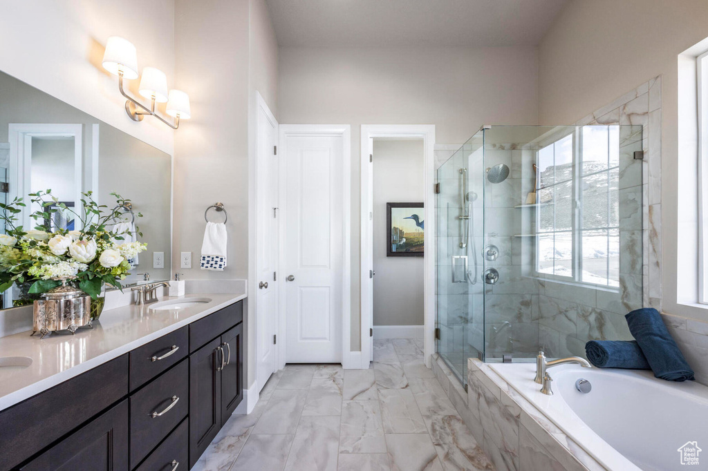 Bathroom with double vanity, a stall shower, a bath, marble finish flooring, and baseboards