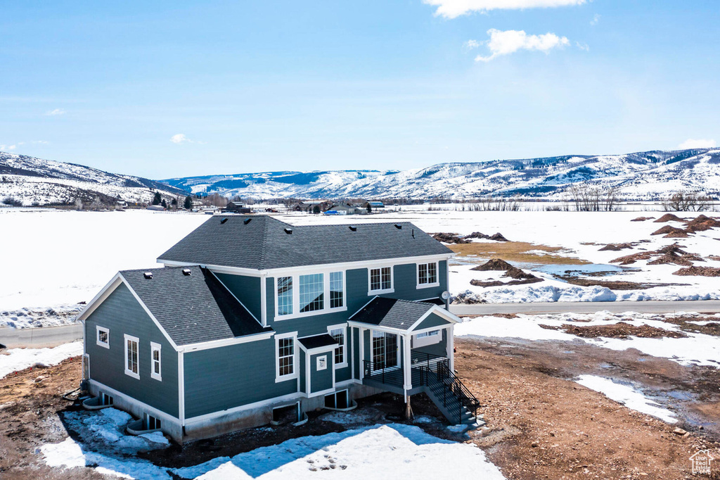 Snow covered house with a shingled roof and a mountain view