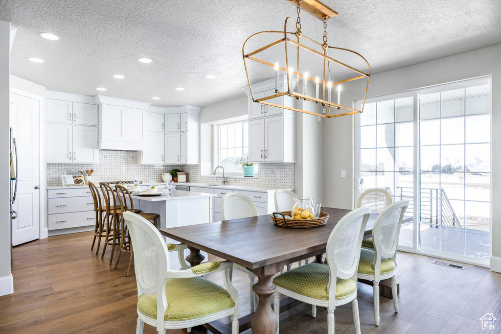 Dining space with a textured ceiling, a chandelier, wood finished floors, and recessed lighting